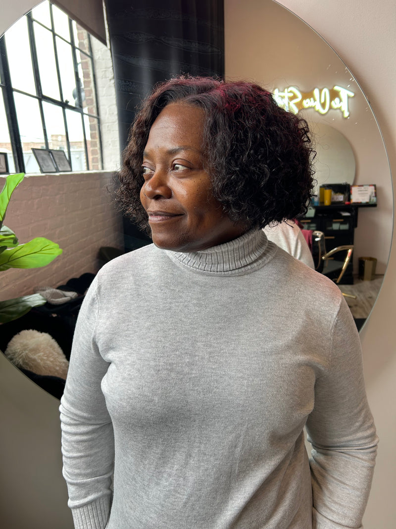 Black woman wearing a curly bob cranial prosthesis with HD lace paid for with HSA benefits 