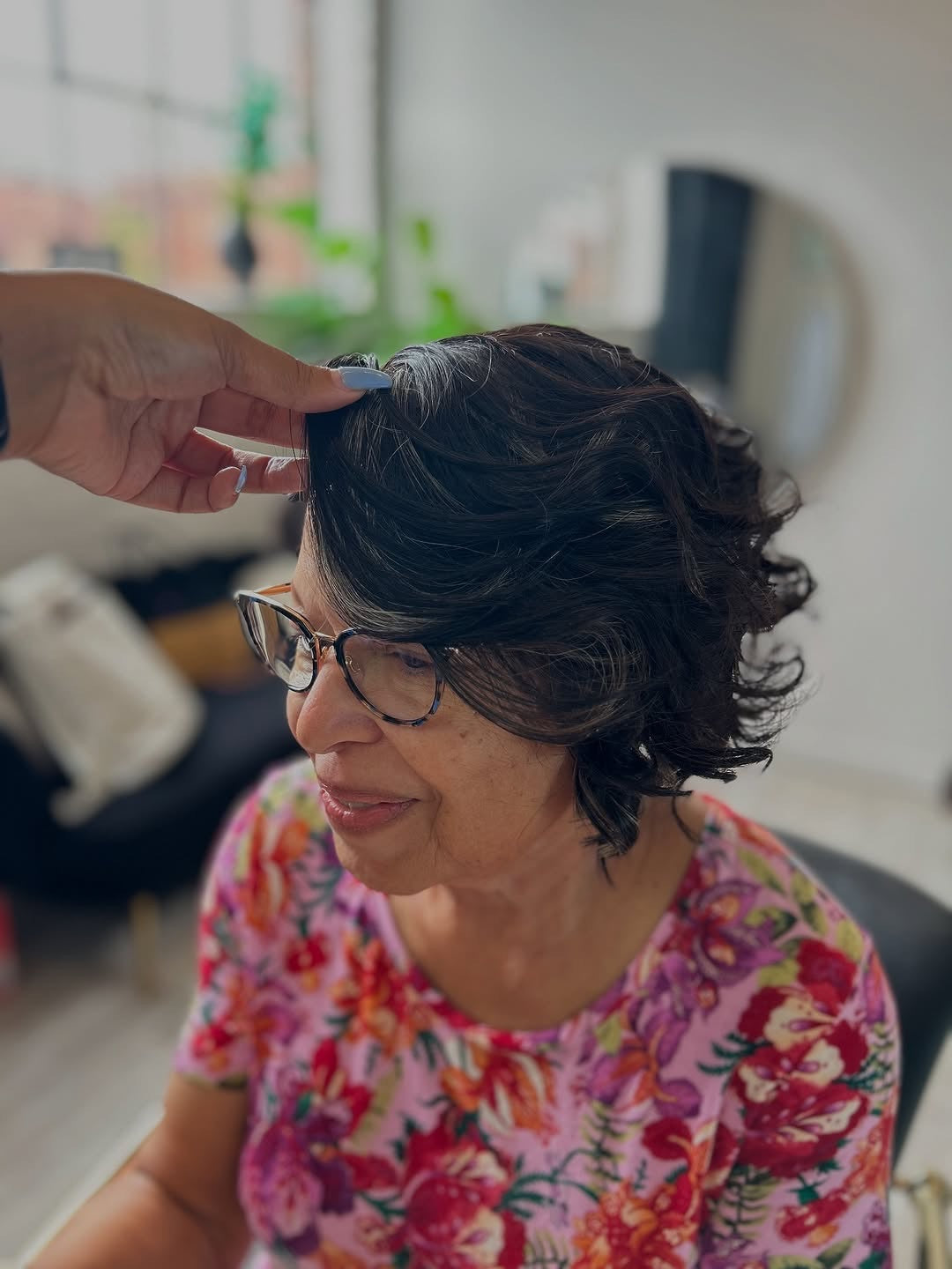 Older woman wearing a bob cranial prosthesis with HD lace that has been curled and has hints of grey