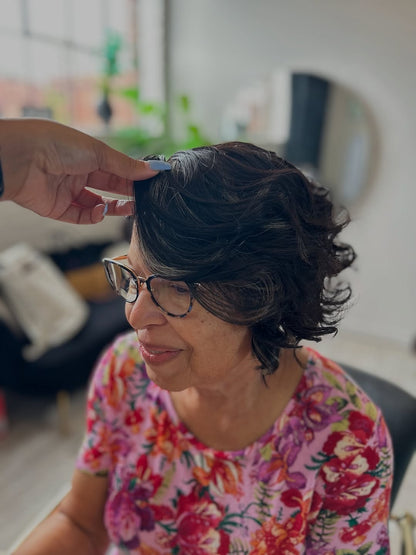 Older woman wearing a bob cranial prosthesis with HD lace that has been curled and has hints of grey